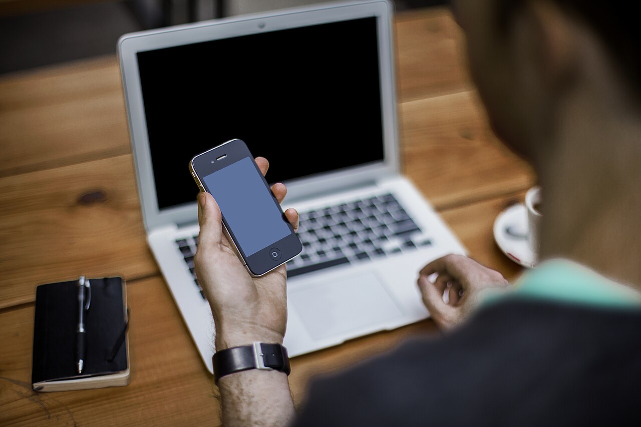 Resident holding a smartphone beside a laptop while choosing a Japanese phone plan