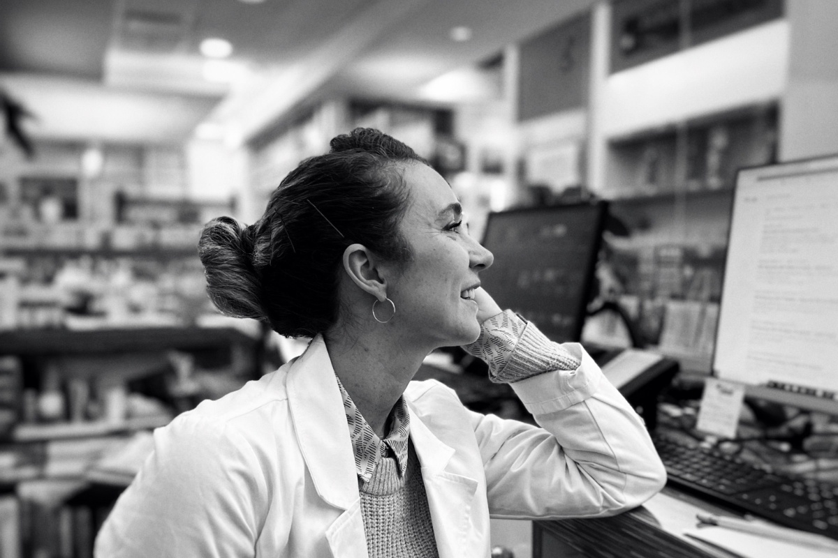 Pharmacist working at a dispensing counter with medicine shelves