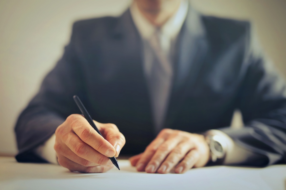 Professional signing employment documents at a desk