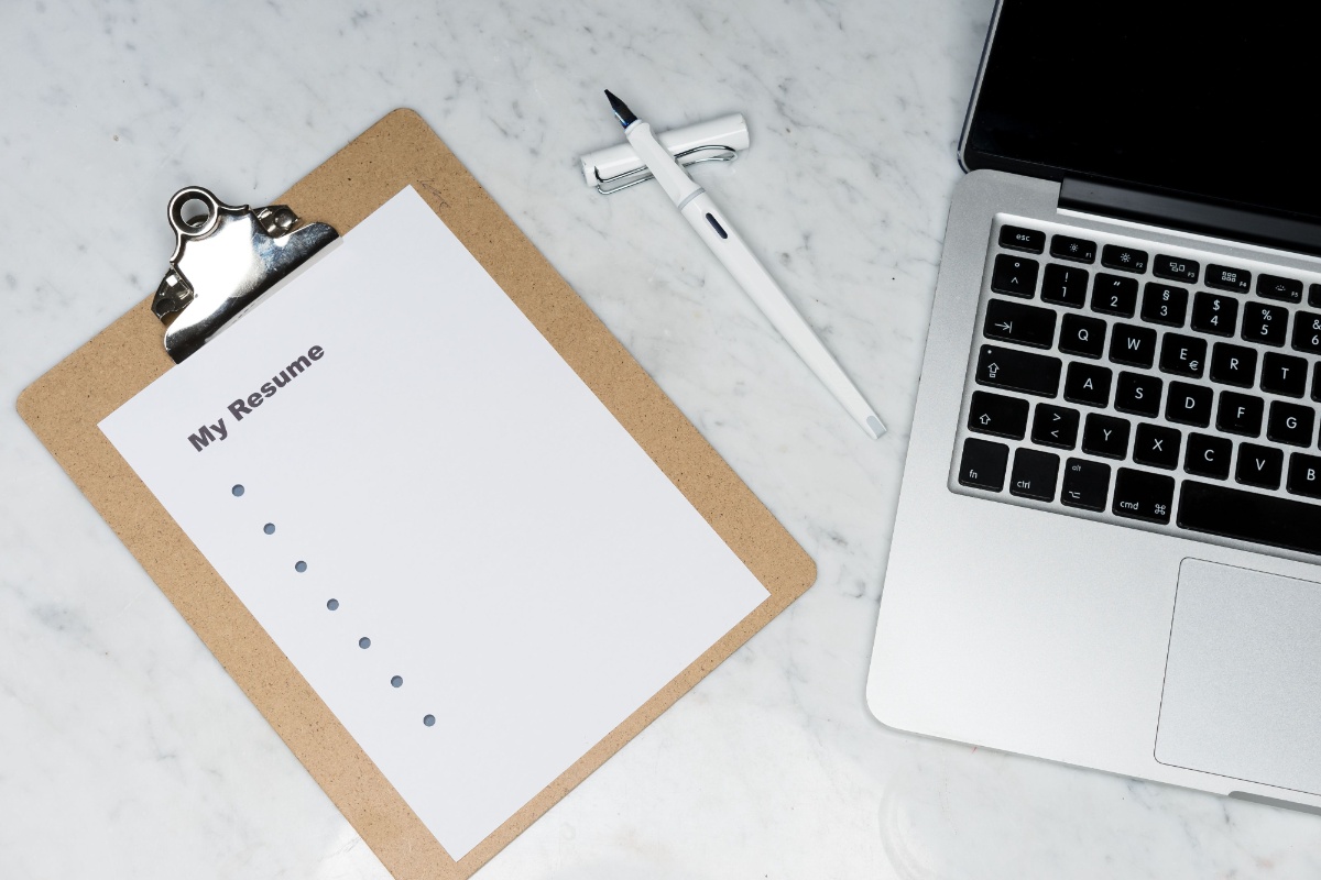 Resume on a clipboard beside a laptop and pen