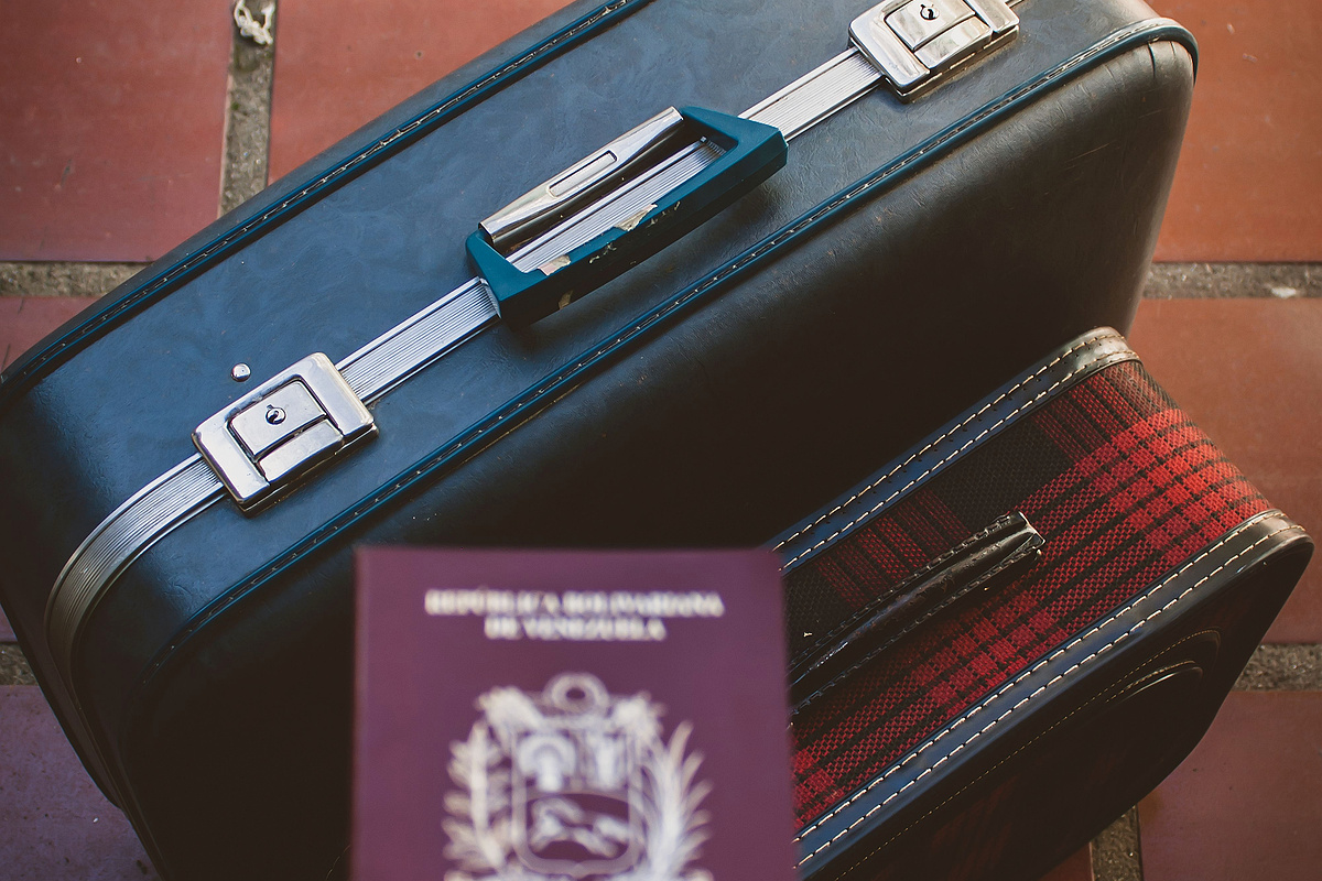 Traveler holding a passport beside luggage after losing a residence card abroad