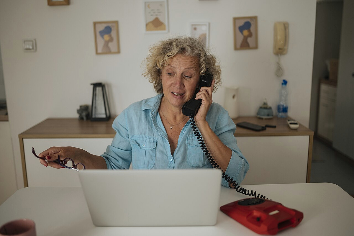 Person speaking on a landline while using a laptop