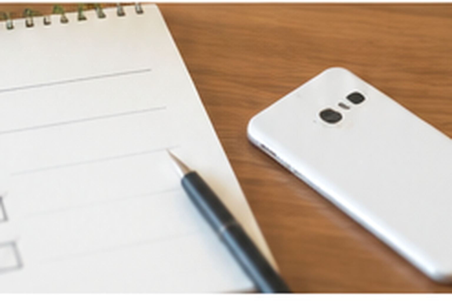 Smartphone beside a blank mobile plan comparison checklist and pen