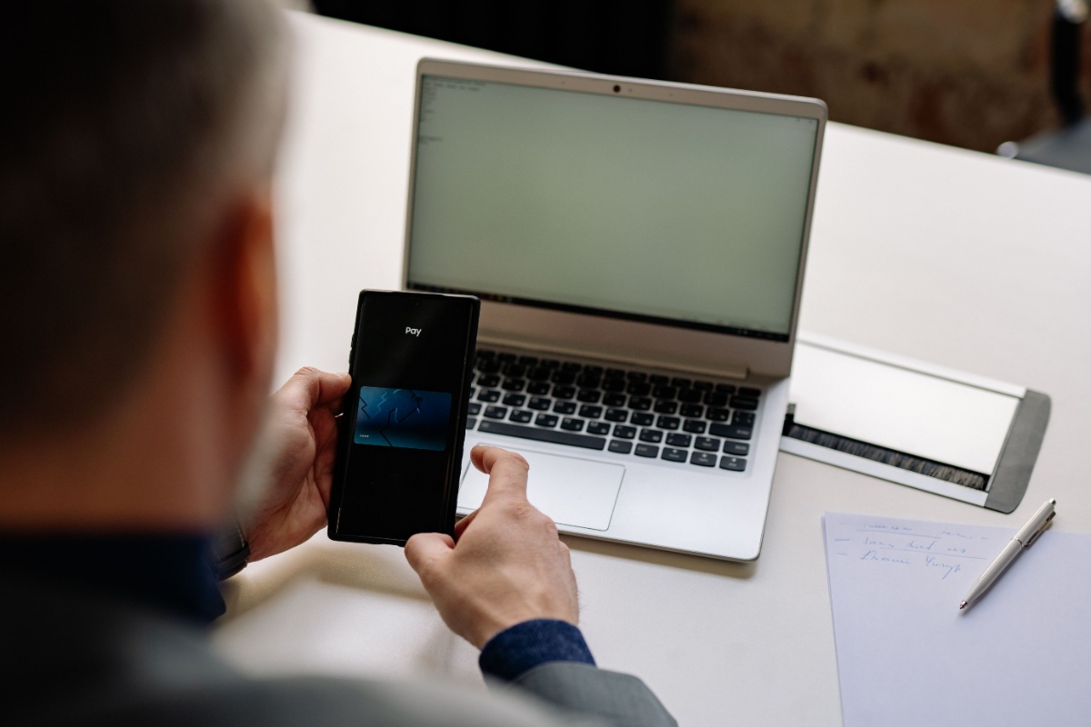 Employee checking payroll information by laptop and smartphone in a modern office