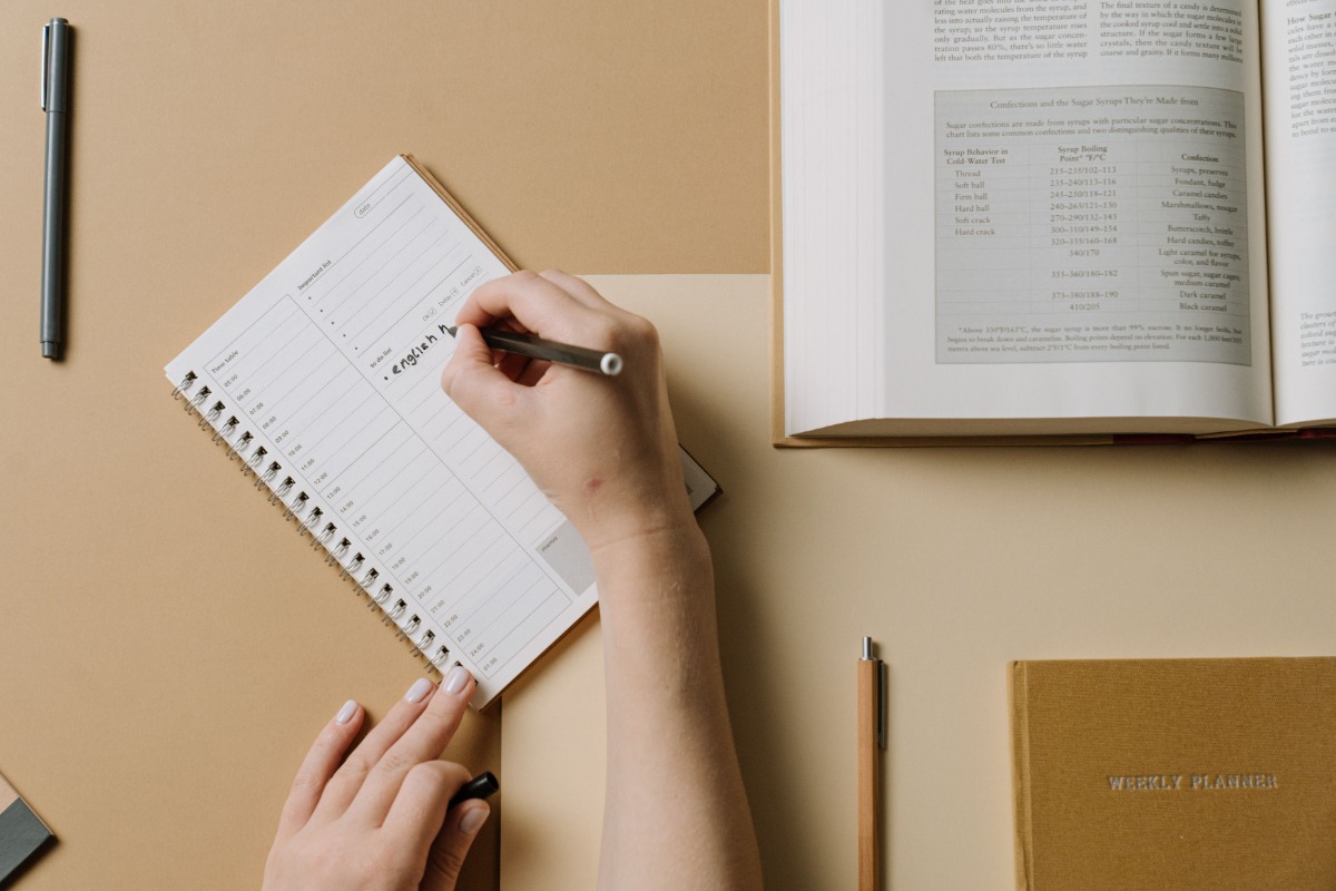 Person writing dates in a paper planner