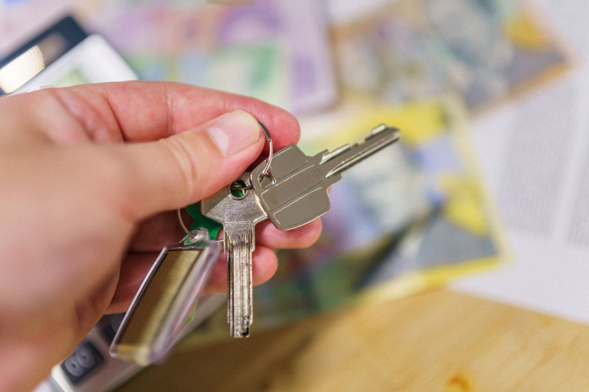 Apartment keys held above rental paperwork