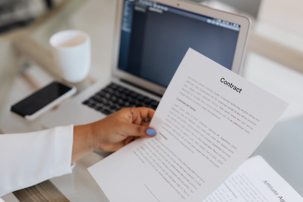 Person reviewing an internet service contract beside a laptop