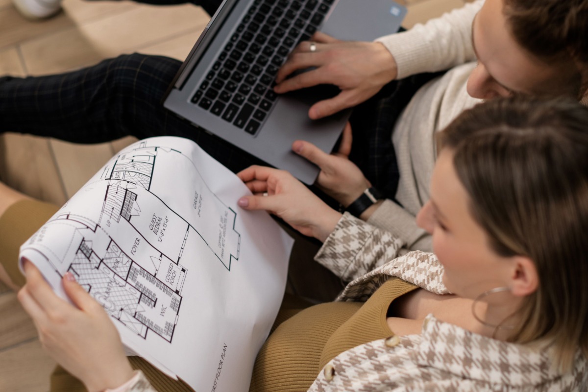 Couple reviewing an apartment floor plan with a laptop