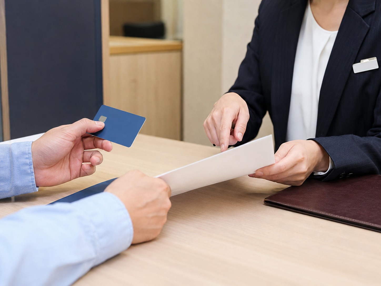Bank staff and resident checking transfer details at a counter in Japan