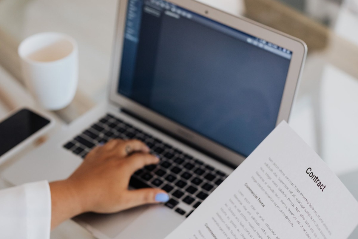 Professional reviewing a work contract beside a laptop