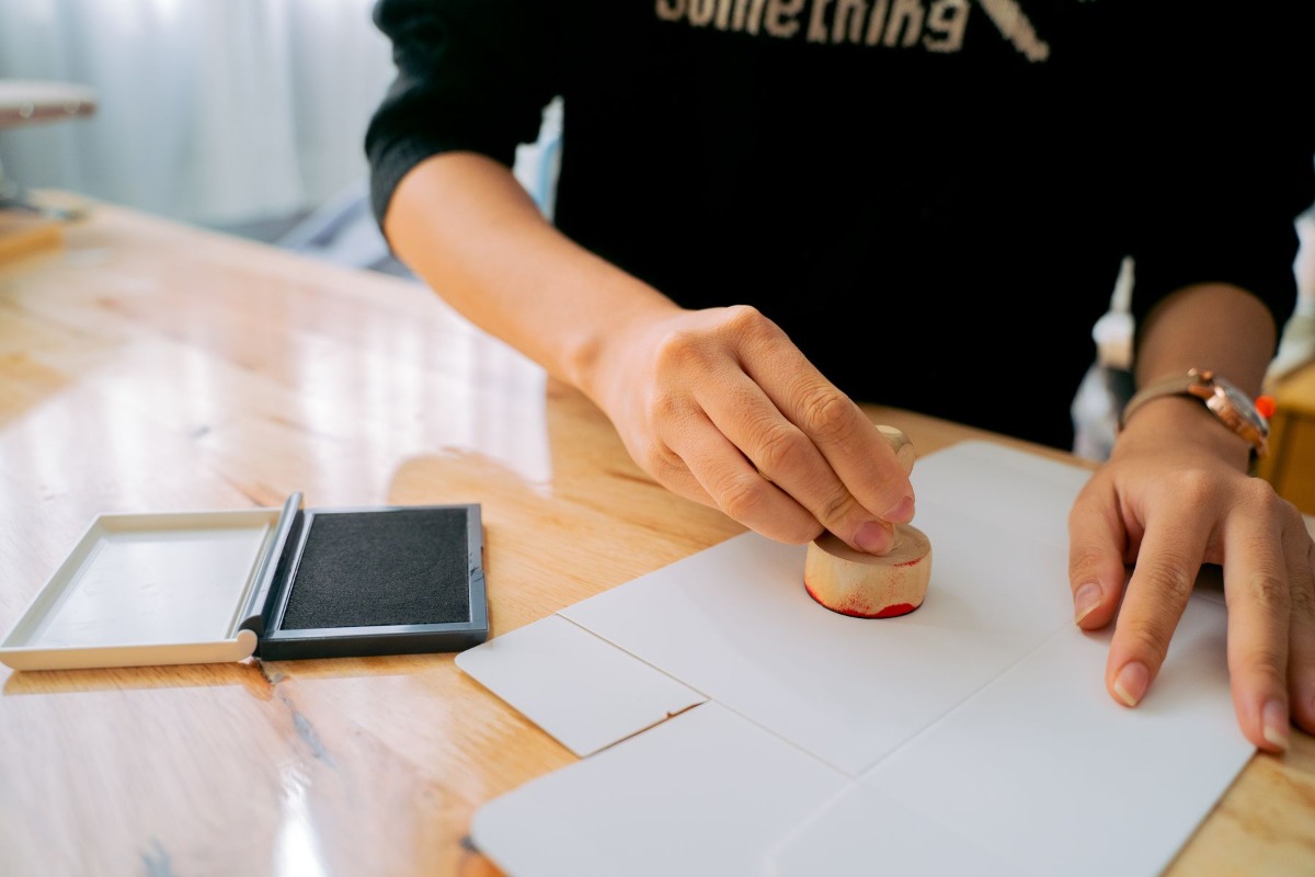 Hands applying a personal stamp to a document