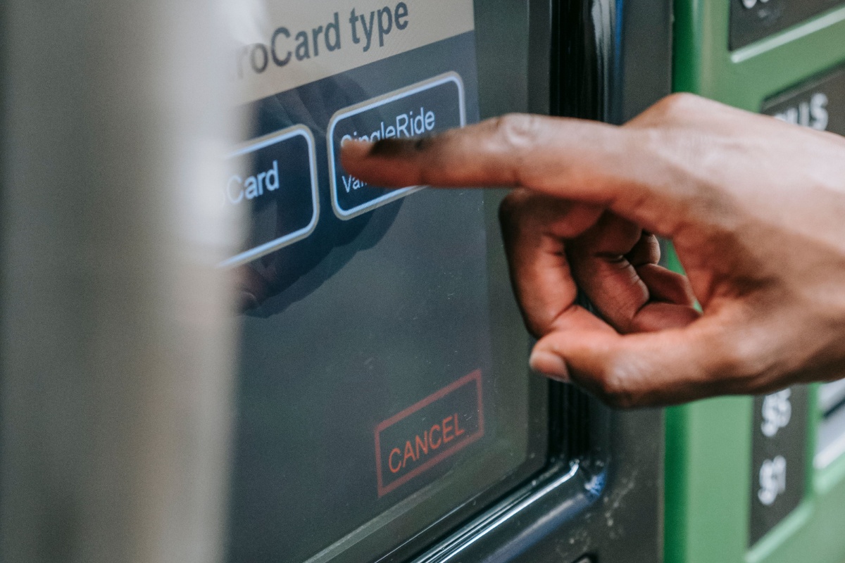 Hand using an ATM touchscreen before confirming a transaction