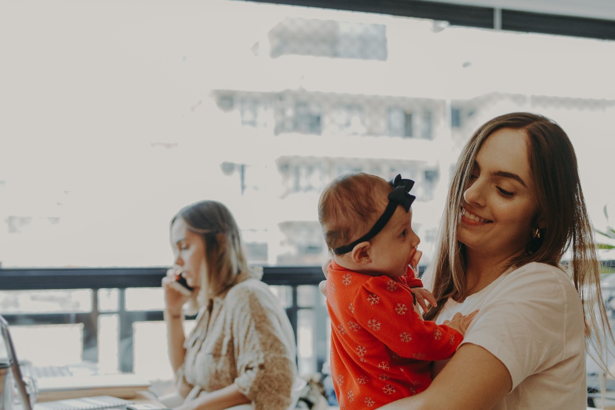 Mother holding a baby while managing family paperwork