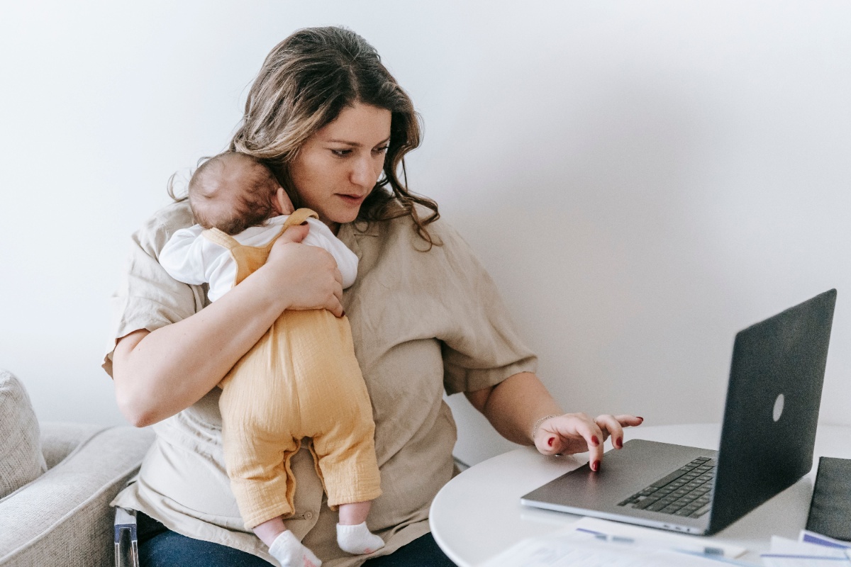 Parent using a laptop while caring for a newborn