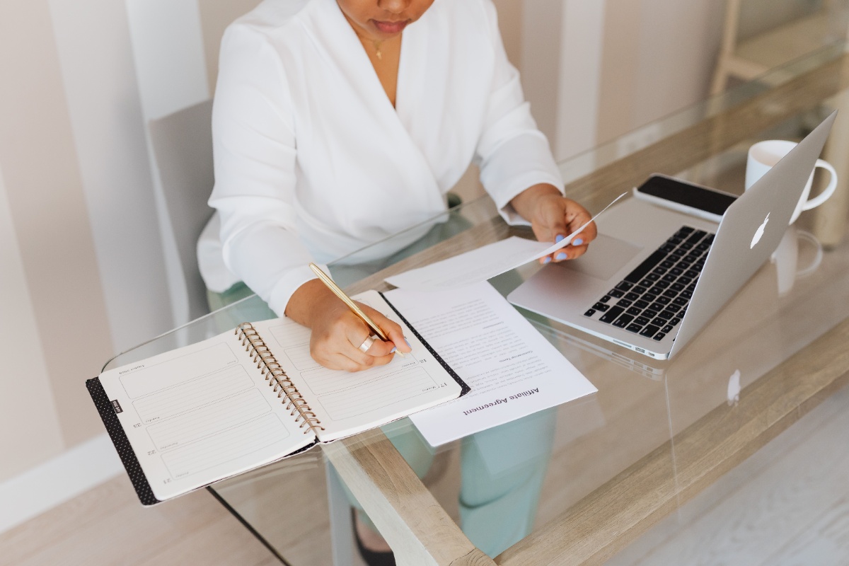 Person checking documents and details beside a laptop
