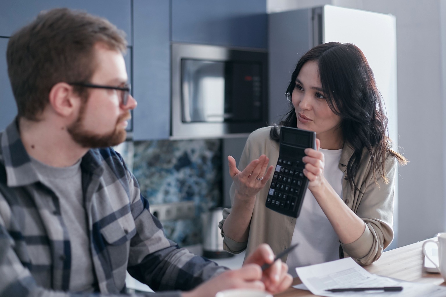 Couple discussing monthly housing costs with a calculator at home
