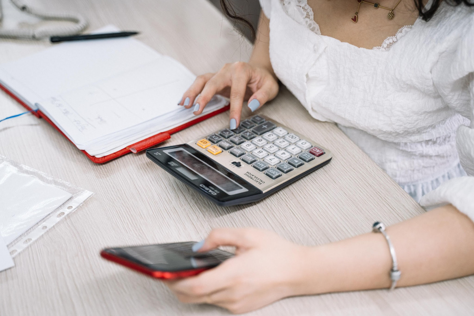 Calculator, smartphone and notebook used to compare monthly mobile costs
